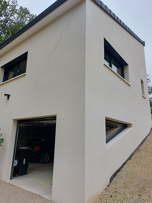 Photo représentant l'extérieur d'une maison avec des fissures apparentes sur le mur
